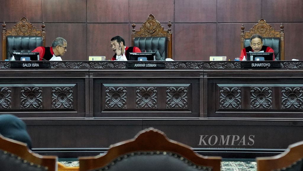 Ketua Mahkamah Konstitusi (MK) Anwar Usman (tengah) berdiskusi dengan hakim MK Saldi Isra (kiri) saat hakim MK Suhartoyo (kanan) membacakan landasan penolakan revisi usia pada sidang putusan uji materiil Pasal 169 huruf q UU Pemilu terkait batas usia minimal calon presiden (capres) dan calon wakil presiden (cawapres) di Mahkamah Konstitusi, Jakarta, Senin (16/10/2023).
