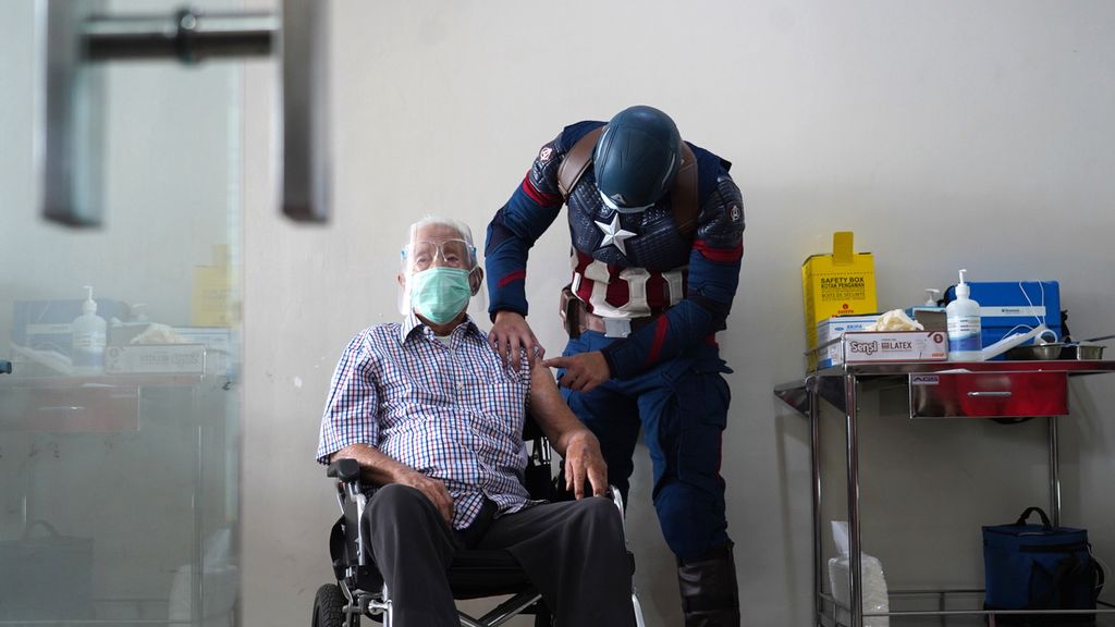 Dokter Rollando Erric Manibuy (kanan) berkostum superhero Captain America memeriksa lengan Wirjawan Hardjamulia (104) di Rumah Sakit Vania, Kota Bogor, Jawa Barat, sebelum di suntik vaksin Covid-19 yang ke dua, Selasa (20/4/2021). 