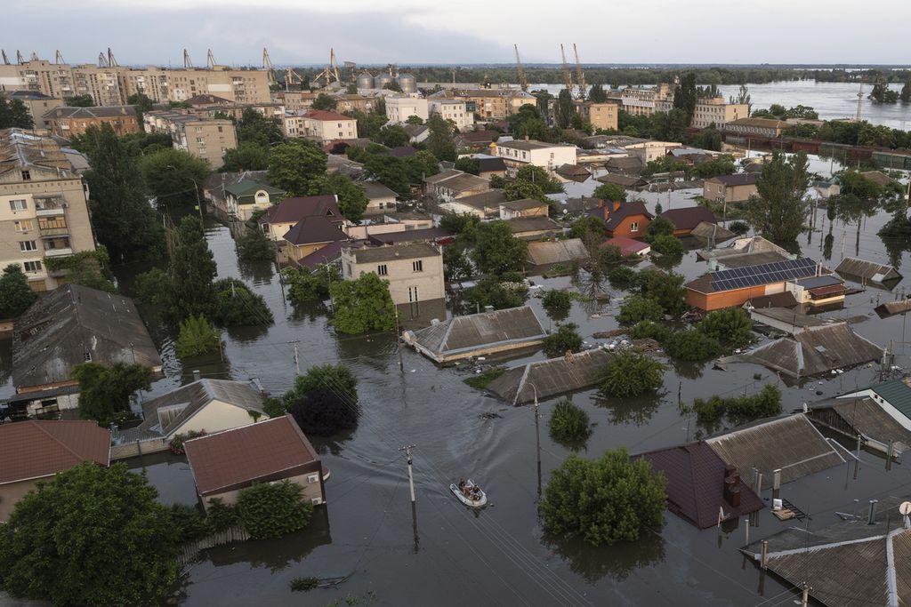 Warga naik perahu karet di tengah-tengah banjir di Kherson, Ukraina, Rabu (7/6/2023).