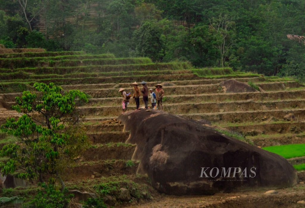 Warga berdiri di atas bongkahan batu setelah istirahat di sekitar lahan sawah mereka di Desa Gembong, Kecamatan Kandangserang, Kabupaten Pekalongan, Jawa Tengah, Sabtu (19//12/2020).