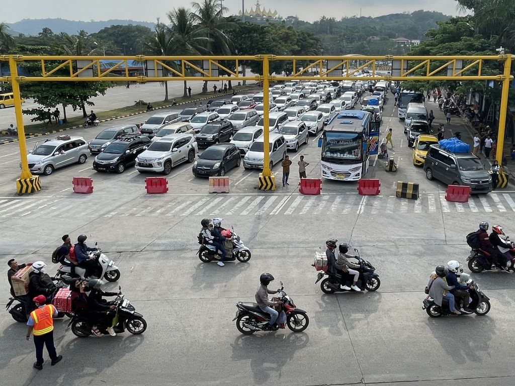 Sepeda motor melintas untuk memasuki kapal, sedangkan kendaraan roda empat atau lebih masih tertahan di kantong parkir di Pelabuhan Bakauheni, Lampung, Minggu (30/4/2023).