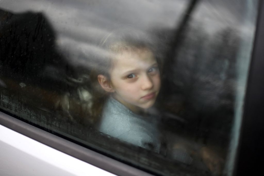Seorang anak Ukraina melihat melalui jendela mobil yang terjebak kemacetan lalu lintas di Desa Tvirzha saat keluarganya berkendara menuju perbatasan Medyka-Shehyni antara Ukraina dan Polandia untuk mengungsi, 28 Februari 2022. 