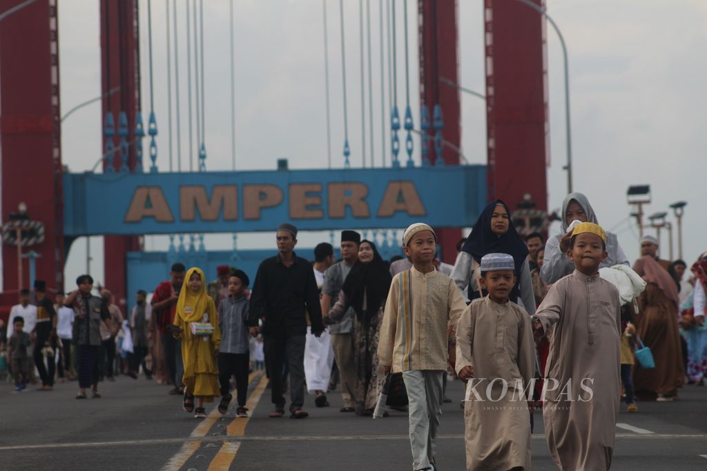 Sejumlah warga sedang berjalan di atas Jembatan Ampera, Palembang, Sumatera Selatan, untuk mengikuti shalat Idul Fitri bersama, Sabtu (22/4/2023). Setelah pemberlakuan pembatasan kegiatan masyarakat (PPKM) dilonggarkan aktivitas tahunan ini kembali ramai diikuti warga dari dalam dan dari luar kota Palembang.
