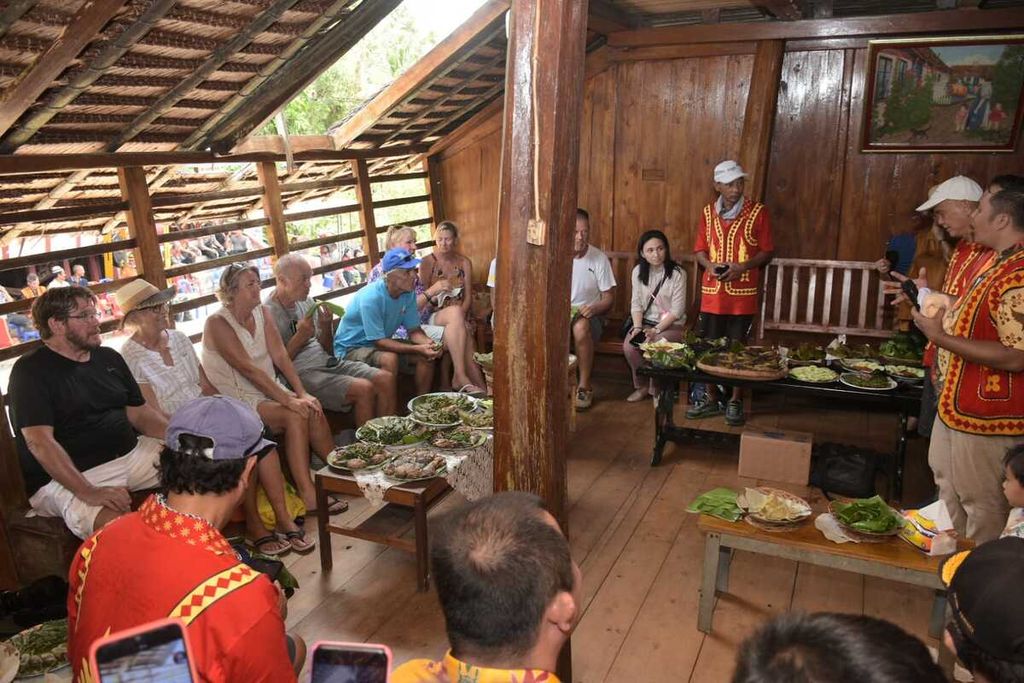 Wisatawan asing rombongan West Sumatera Yacht Rally 2022 menikmati suguhan makanan tradisional di rumah adat Nias di desa adat Desa Tumöri, Kecamatan Gunungsitoli Barat, Kota Gunungsitoli. Sumatera Utara, Sabtu (2/4/2022). Pariwisata berbasis kebudayaan dan bahari menjadi daya tarik Nias. 