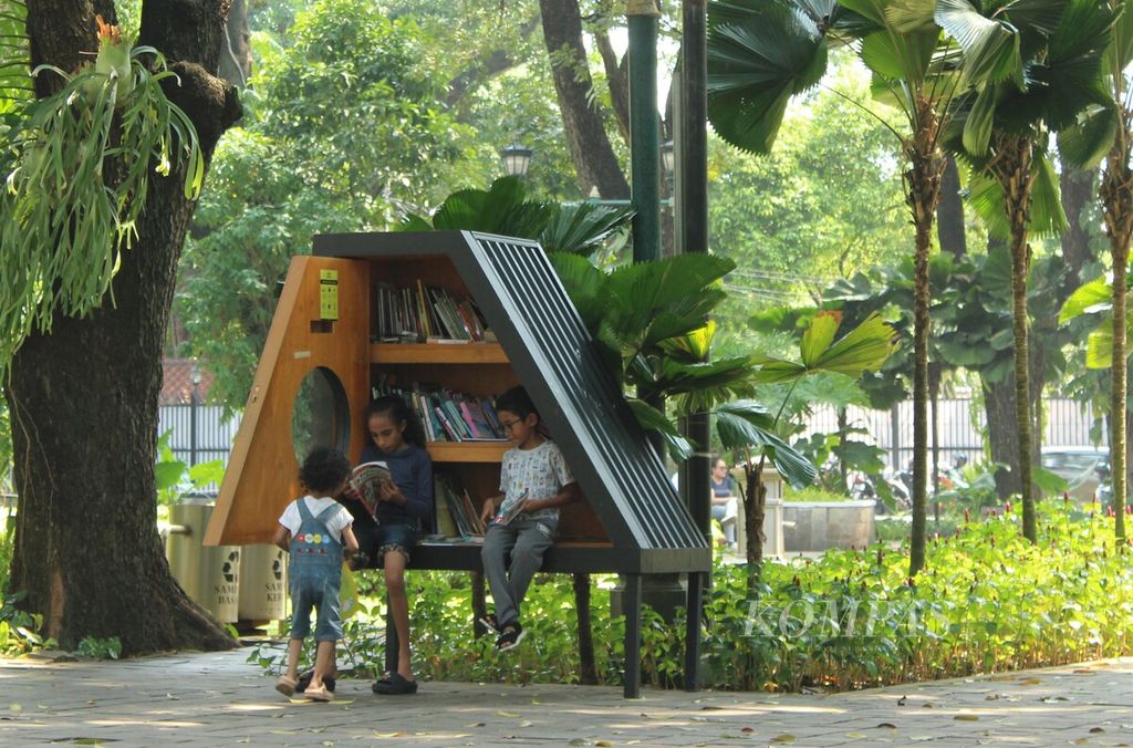 Anak-anak membaca buku yang diambil dari lemari buku Bookhive di Taman Suropati, Menteng, Jakarta Pusat, Senin (24/4/2023). Lemari buku di taman itu mempermudah masyarakat mengakses bahan bacaan sehingga diharapkan meningkatkan minat baca.