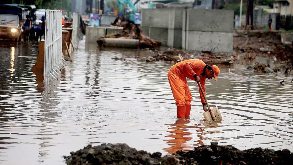 Petugas kebersihan berusaha membuang air yang menggenangi Jalan DI Panjaitan, Jatinegara, Jakarta Timur, setelah turun hujan, Kamis (18/1). Buruknya drainase ditambah adanya proyek pembangunan Tol Becakayu di tempat tersebut menyebabkan air sulit terbuang.