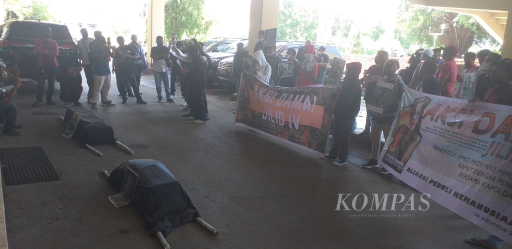 Dua keranda jenazah lambang kematian Astrit Manafe (30) dan anaknya, Lael Maccabe (1), yang diusung massa demonstran diletakkan di depan pintu Gedung DPRD NTT di Kupang, Senin (10/1/2022).
