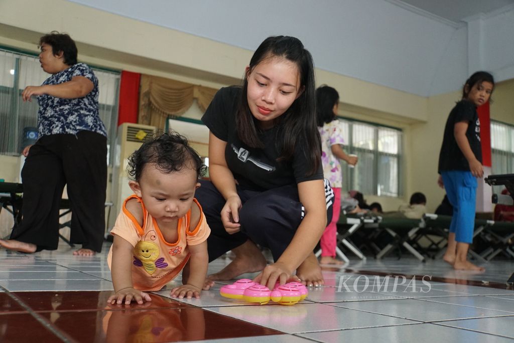 Ferawati Noho (18) bermain bersama kemenakannya di pusat pengungsian korban banjir di aula markas Komando Resor Militer (Korem) 131/Santiago di Manado, Sulawesi Utara, Sabtu (28/1/2023). Sehari sebelumnya, Manado dilanda banjir dan tanah longsor yang menewaskan sedikitnya lima orang.
