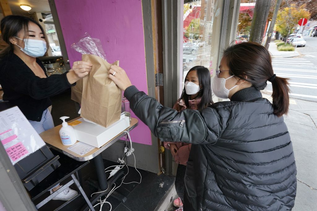 Kyung Kim (kanan) bersama putrinya, Alexa Oh (9), berbelanja makanan dengan memperhatikan protokol kesehatan seperti mengenakan masker dan menjaga jarak di Seattle, Kamis (12/11/2020). 