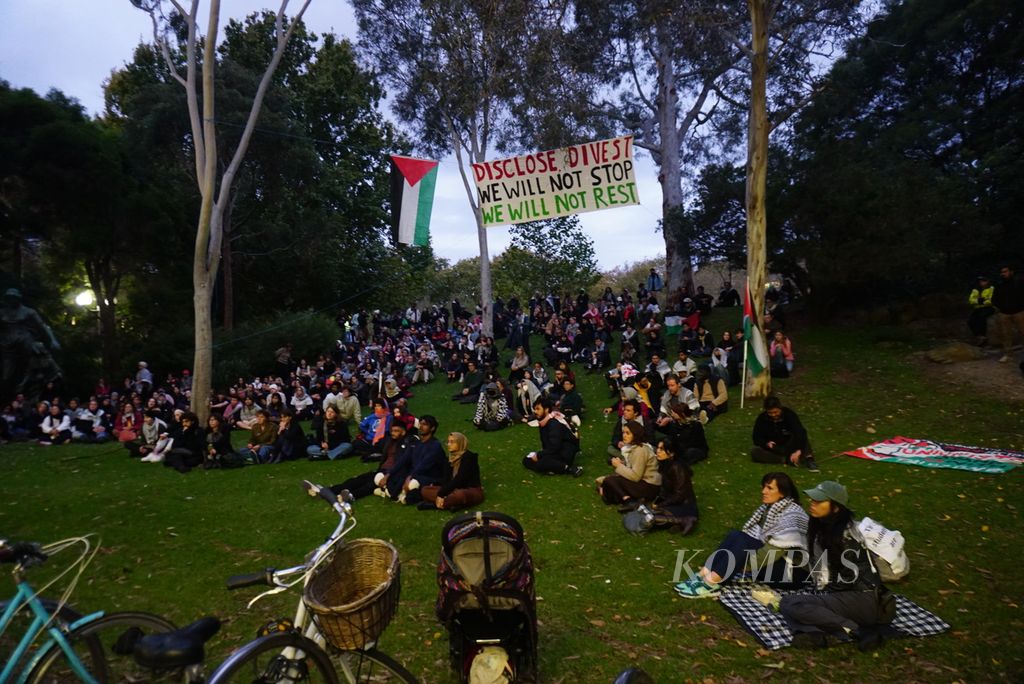 Para mahasiswa mendengarkan orasi dalam gelaran protes di kampus Parkville Universitas Melbourne di Melbourne, Australia, Senin (29/4/2024), untuk meminta penghentian kerja sama perguruan tinggi tersebut dengan beberapa perusahaan yang memasok senjata ke Israel. 
