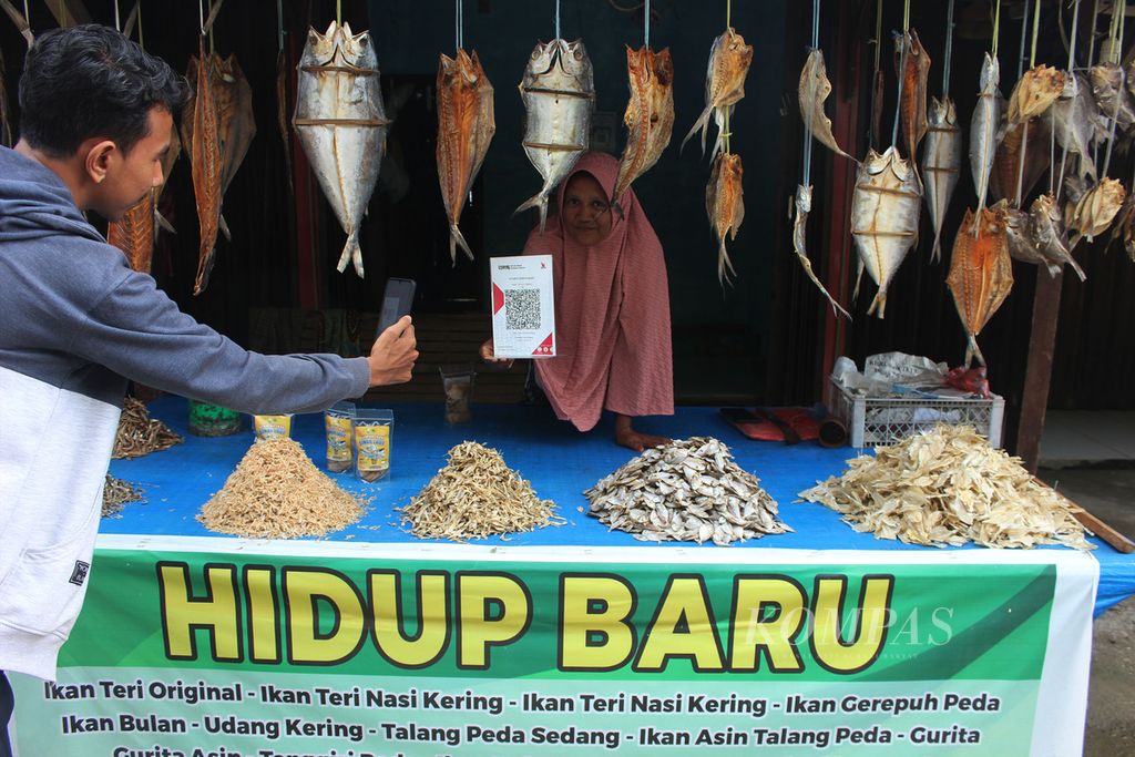 Ilustrasi. Pembeli melakukan pindai kode batang untuk membayar saat membeli produk usaha mikro, kecil, dan  menengah (UMKM) di sentra penjualan ikan asin di Kecamatan Leupung, Kabupaten Aceh Besar, Aceh, Kamis (21/6/2022). 