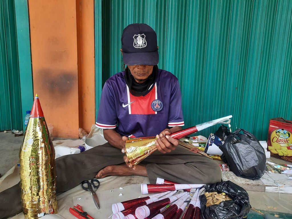Rojali (50) menyambung kerucut dan batang trompet kertas di kawasan Kota Tua, Jakarta, Sabtu (31/12/2022). Sehari-hari, ia bekerja sebagai buruh lepas di Cikarang, Jawa Barat.