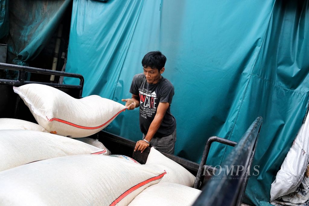 Pekerja meletakkan karung beras ke dalam angkutan bak terbuka di Pasar Induk Beras Cipinang, Jakarta, Sabtu, (26/2/2022). 
