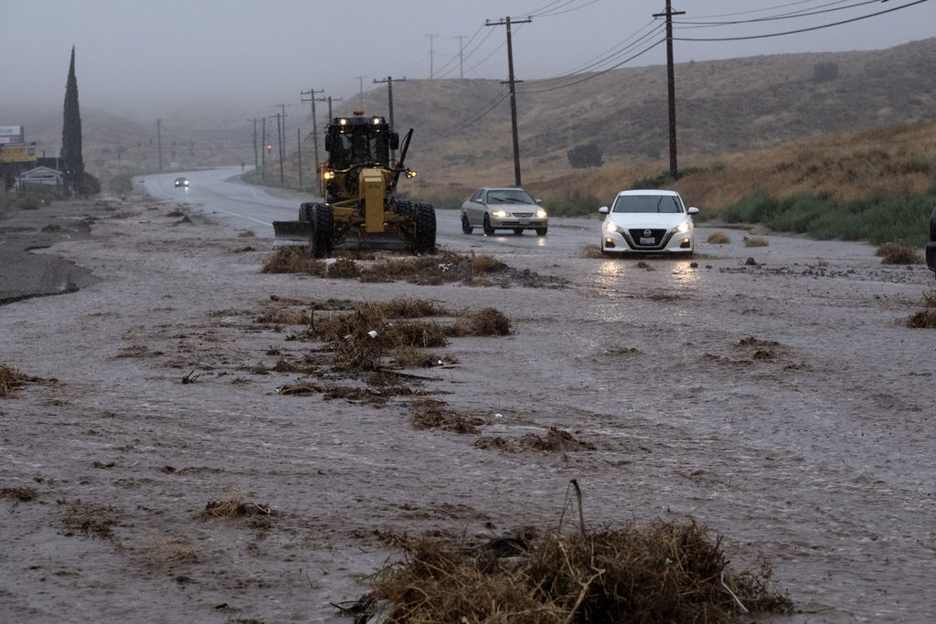 Mobil bermanuver melewati genangan banjir dan puing-puing di sepanjang Sierra Highway, Palmdale, California, saat Badai Tropis Hilary bergerak melalui area itu Minggu (20/8/2023). 