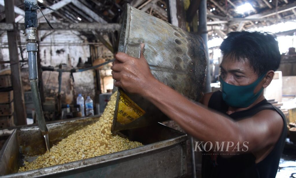 Pekerja menggiling kacang kedelai untuk pembuatan tahu di Pabrik Tahu Sumber Kencana, Surabaya, Jawa Timur, Senin (4/1/2021). 
