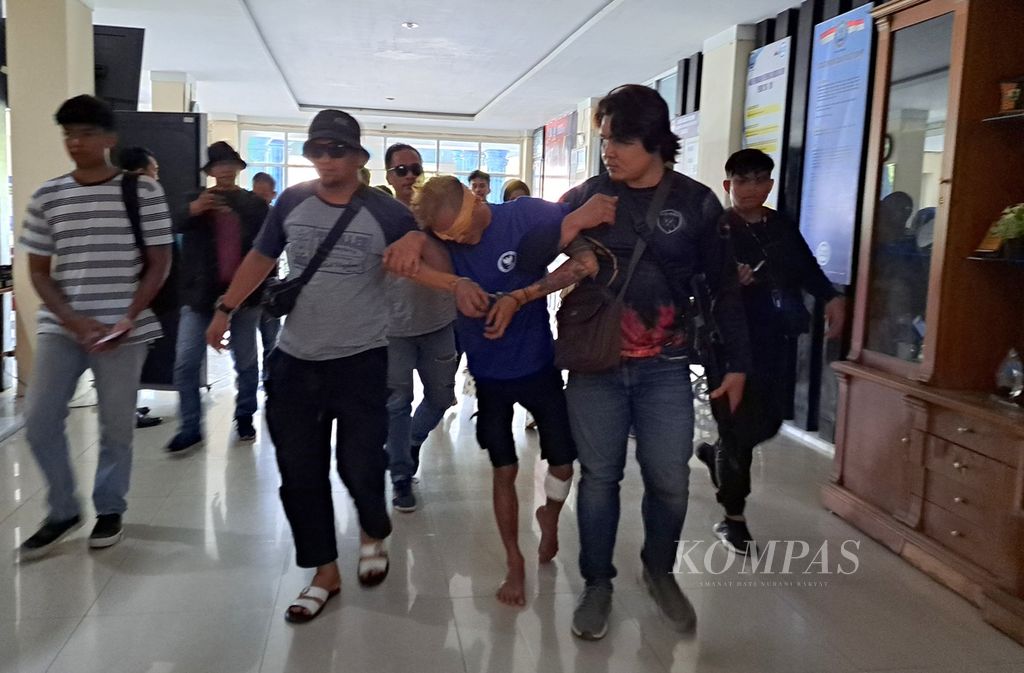 Doris Adha Putra (29), pengedar narkotika, berjalan pincang dibantu petugas di kantor BNNP Sumbar, Padang, Rabu (31/5/2023).