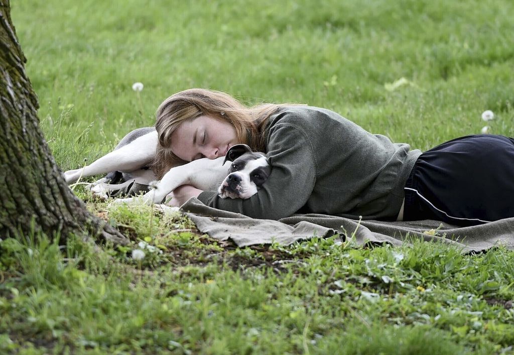 Seorang perempuan dan anjingnya tidur siang di Schenley Park, AS, pada 4 Mei 2021. Survei Gallup pada 15 April 2024 menyebutkan, mayoritas warga AS akan merasa lebih baik jika bisa tidur lebih banyak. 