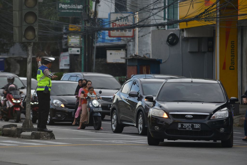 Polisi mengatur lalu lintas di Jalan Mampang Prapatan, Jakarta Selatan, Minggu (20/11/2022). Semenjak peniadaan tilang manual pada 23 Oktober 2022 silam, pelanggar lalu lintas kian marak.