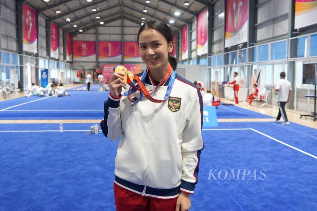 Atlet mahasiswa Indonesia dari cabang olahraga wushu, Nandhira Mauriskha, menunjukkan dua medali emas yang diraihnya di Pekan Olahraga Mahasiswa Sedunia atau Universiade di Chengdu, China, Minggu (30/7/2023). Dia mendapat prestasi tertinggi di nomor <i>changquan </i>(tangan kosong) dan <i>jianshu </i>(pedang) pada disiplin <i>taolu </i>atau keindahan gerakan.