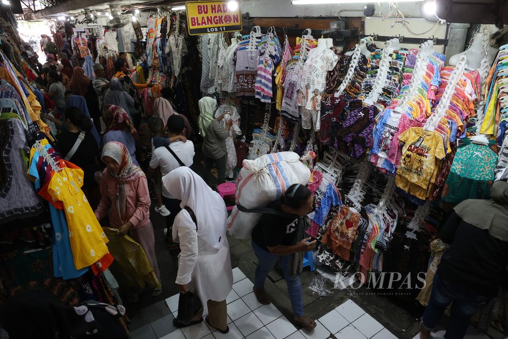 Buruh gendong mengangkut barang melewati area penjualan pakaian di Pasar Beringharjo, Yogyakarta, Rabu (28/12/2022). 
