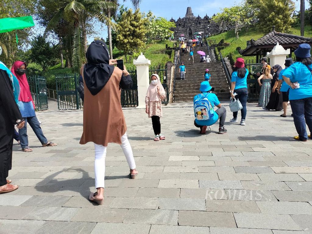 Wisatawan asyik berfoto-foto di depan tangga naik menuju pelataran Candi Borobudur, Senin (4/7/2022).