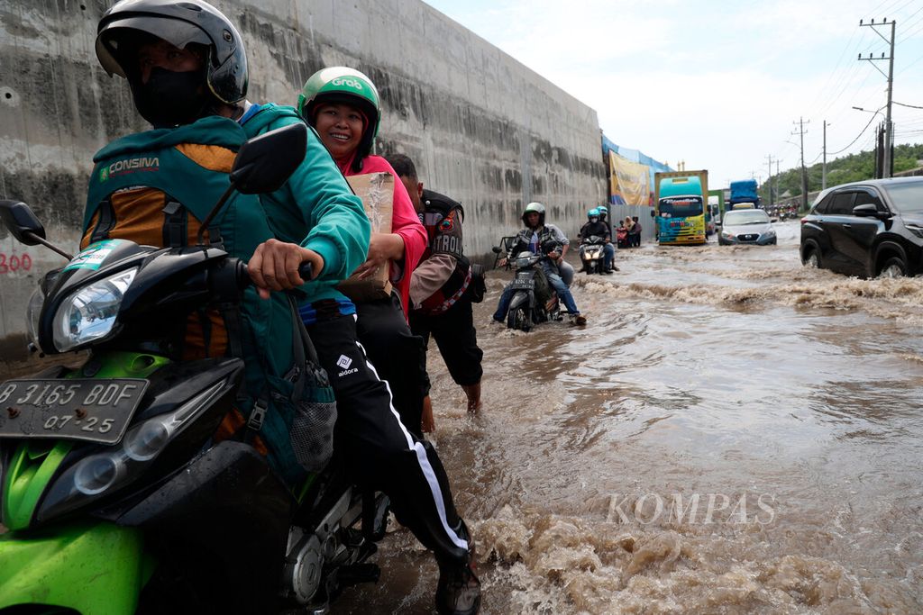 Polisi membantu mendorong kendaraan pemudik yang mogok melintasi genangan banjir di jalur pantura, Kaligawe, Kota Semarang, Jawa Tengah, Sabtu (6/4/2024). Banjir yang terjadi di kawasan tersebut berpotensi menyebabkan kemacetan panjang saat bersamaan dengan arus mudik. 