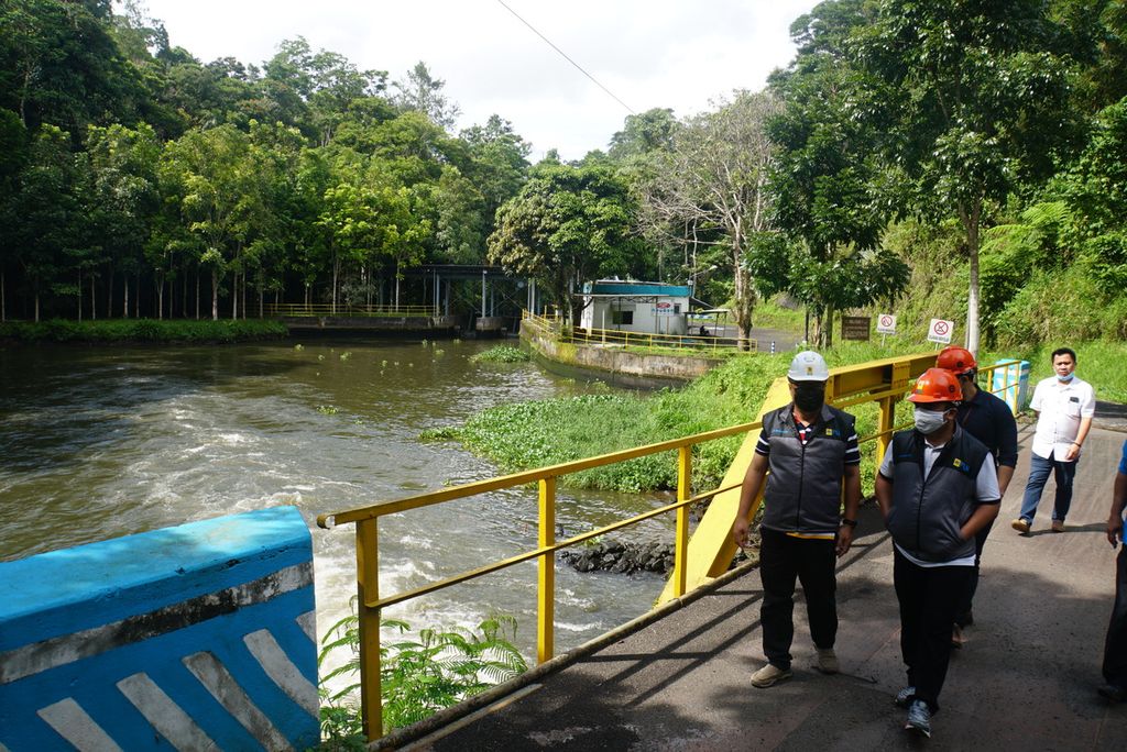 Staf Unit Pelaksanaan Pengendalian dan Pembangkitan (UPDK) Minahasa PT PLN menyusuri jembatan di atas aliran keluar dari PLTA Tonsealama di Minahasa, Sulawesi Utara, pada Rabu (17/2/2021). PLTA berkapasitas terpasang 14,38 megawatt yang mulai didirikan pada 1921 itu masih beroperasi hingga kini dengan tiga mesin, salah satunya sudah berusia lebih dari 100 tahun.