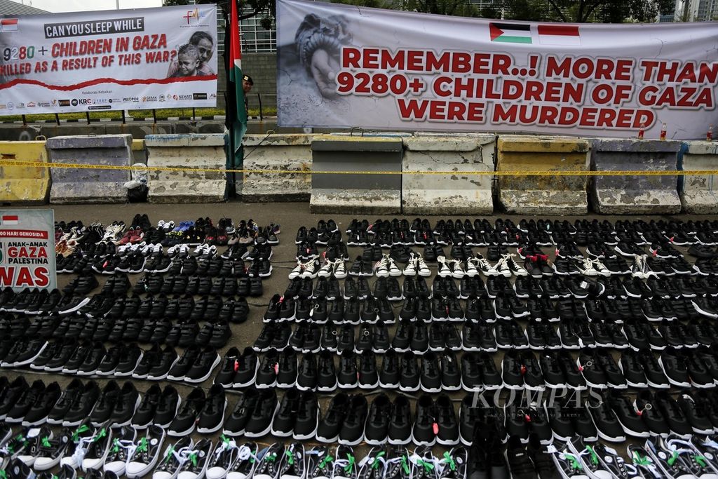 Ribuan sepatu sekolah dipasang berderet di seberang gedung Kedubes Amerika Serikat di Jakarta, saat Filantrop Muda Indonesia menggelar aksi damai untuk memperingati 100 hari genosida Gaza oleh pasukan Israel, Senin (15/1/2024). 