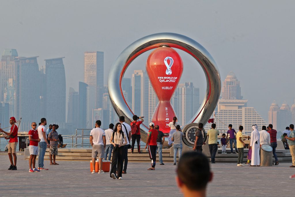 Foto yang diambil pada 20 Oktober 2022 memperlihatkan orang-orang beraktivitas di dekat jam hitung mundur Piala Dunia Qatar 2022 di Doha.  