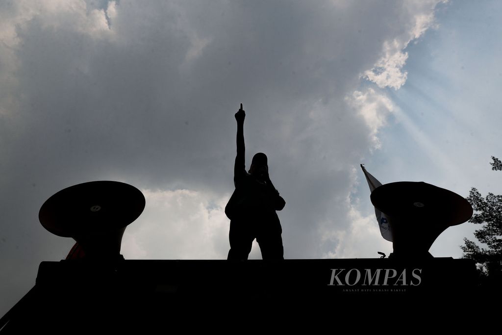 Siluet orator saat berorasi di depan kantor Kementerian Ketenagakerjaan, Jakarta, Kamis (21/9/2023). Puluhan peserta aksi yang terdiri dari Partai Buruh dan sejumlah organisasi buruh menuntut pemerintah menaikkan upah minimum sebesar 15 persen pada 2024.