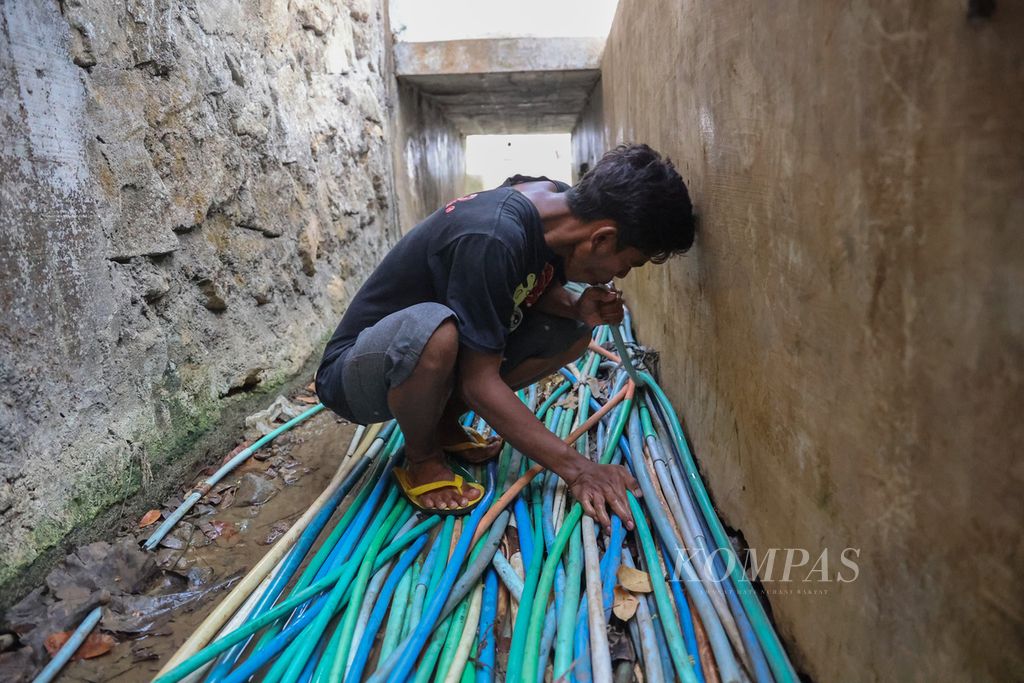 Warga menyedot air melalui selang yang terhubung ke mata air untuk mengalirkan air ke rumahnya di Desa Selopamioro, Kabupaten Bantul, Daerah Istimewa Yogyakarta, Selasa (31/10/2023).