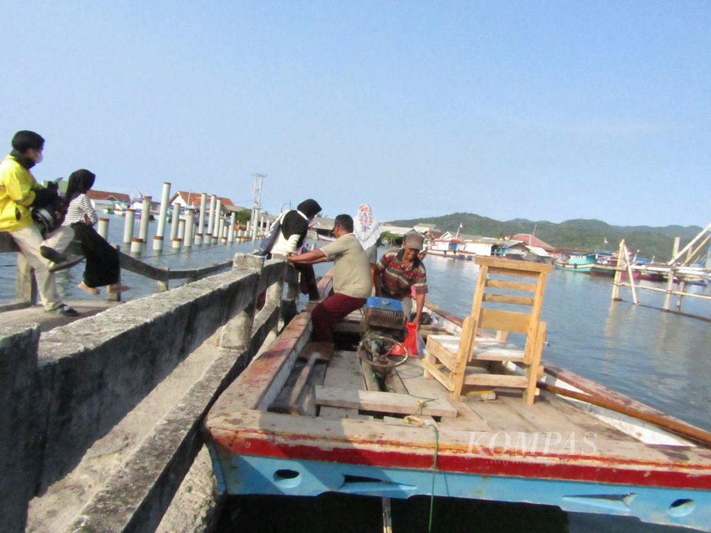 Warga Pulau Pasaran, Bandar Lampung menyeberang menggunakan perahu kayu, Rabu (18/5/2022). Warga menyeberang menggunakan perahu kayu karena jembatan terendam banjir rob sejak tiga hari terak