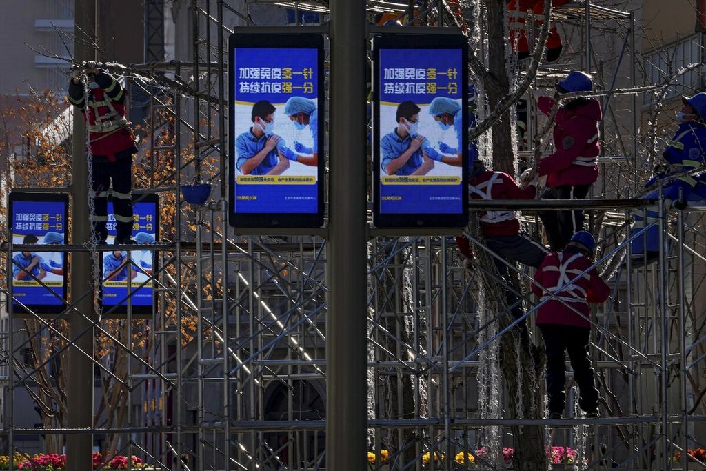 Pekerja memasang lampu hias di pohon untuk perayaan Tahun Baru di Beijing, China (26/12/2021). China membatalkan ratusan penerbangan pada masa liburan akhir tahun karena lonjakan kasus korona.