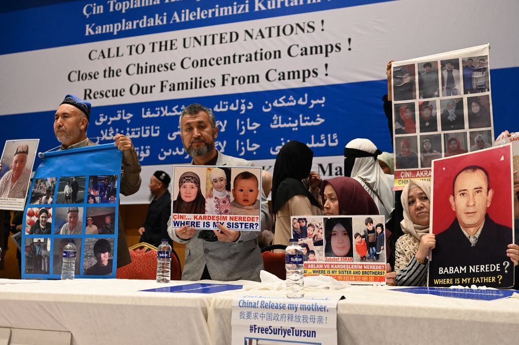 Foto yang direkam pada 10 Mei 2022 ini memperlihatkan sejumlah warga Uighur memperlihatkan foto keluarga dan kerabat mereka yang masih ditahan di Pusat Pendidikan dan Latihan Kejuruan (VETC) di beberapa wilayah di Xinjiang, China, atas alasan terorisme.