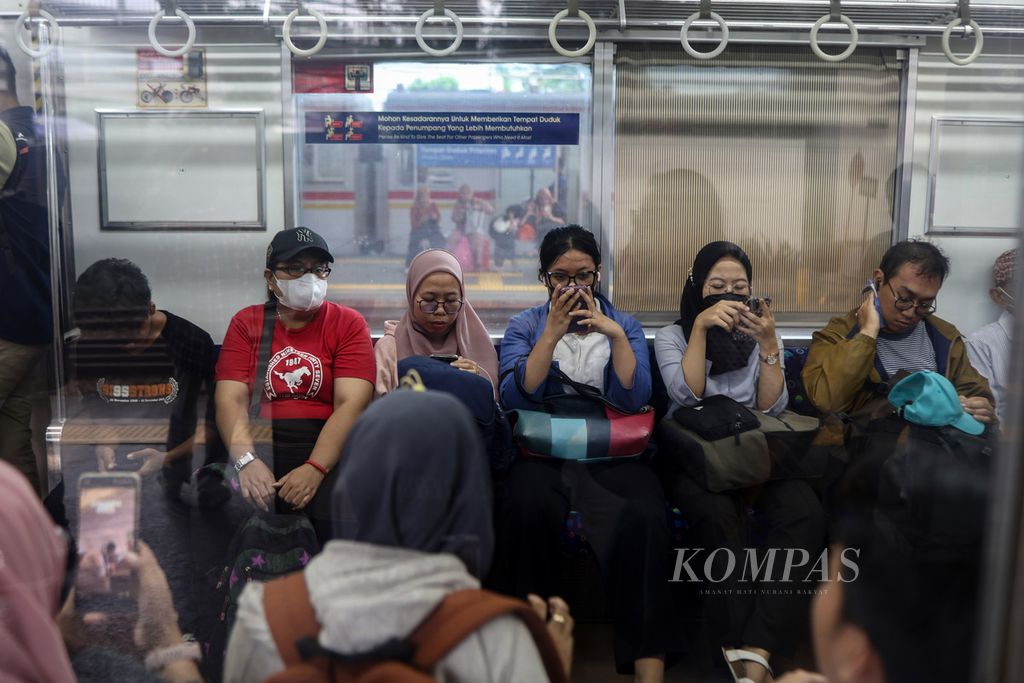 Sejumlah warga menggunakan ponsel saat menunggu kereta komuter berangkat dari Stasiun Tanah Abang, Jakarta, Jumat (26/4/2024).