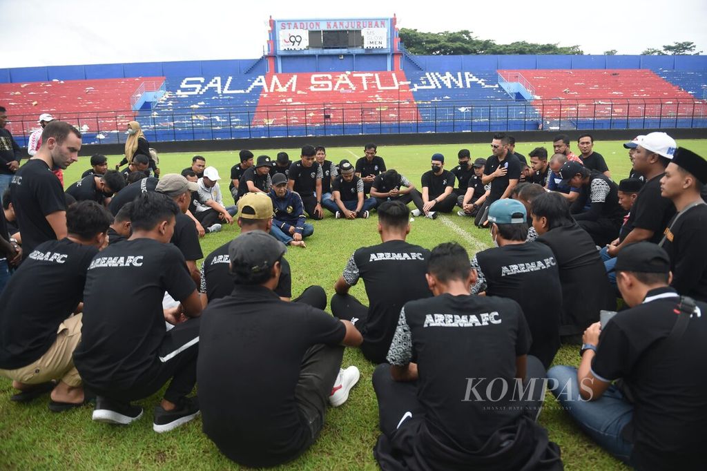 Pemain dan ofisial Arema FC berada di tengah lapangan di Stadion Kanjuruhan untuk memberikan penghormatan bagi korban yang meninggal saat kerusuhan, di Kabupaten Malang, Jawa Timur, Senin (3/10/2022). 