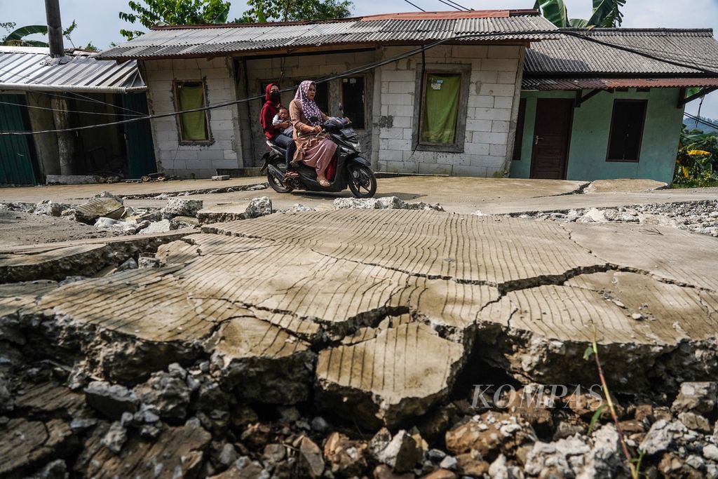 Warga melintasi rumah dan jalan di Kampung Curug, Desa Bojong Koneng, Kecamatan Babakan Madang, Kabupaten Bogor, Jawa Barat, yang rusak akibat tanah bergerak, Rabu (21/9/2022). 