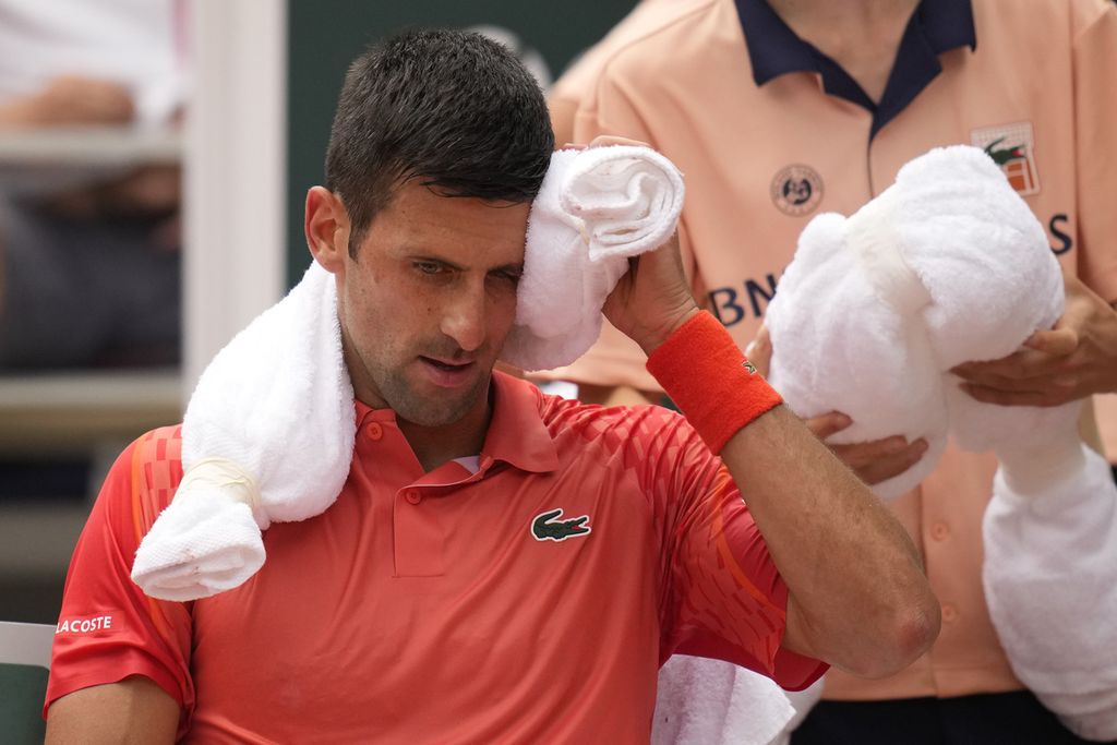 Novak Djokovic menyeka wajahnya dengan handuk berisi es batu saat jeda pada laga final Grand Slam Perancis Terbuka melawan Casper Ruudd di Roland Garros, Paris, Minggu (11/6/2023).