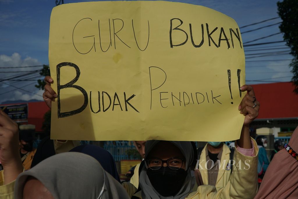 Mahasiswa memegang karton bertuliskan kritik dalam unjuk rasa peringatan Hari Guru Nasional di Jalan Sudirman depan Kantor Gubernur Sumatera Barat, Kota Padang, Sumatera Barat, Kamis (25/11/2021).