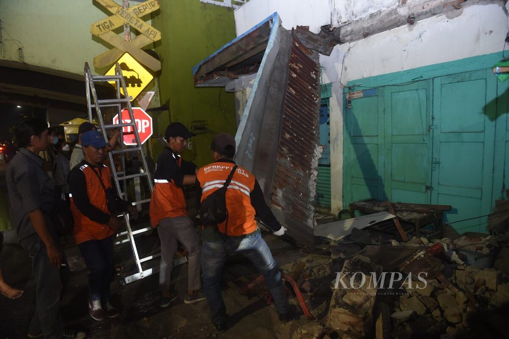 Petugas berusaha mencopot bagian atap bangunan di Jalan Ngaglik, Kota Surabaya, Jawa Timur, yang rusak setelah gempa, Jumat (22/3/2024). 