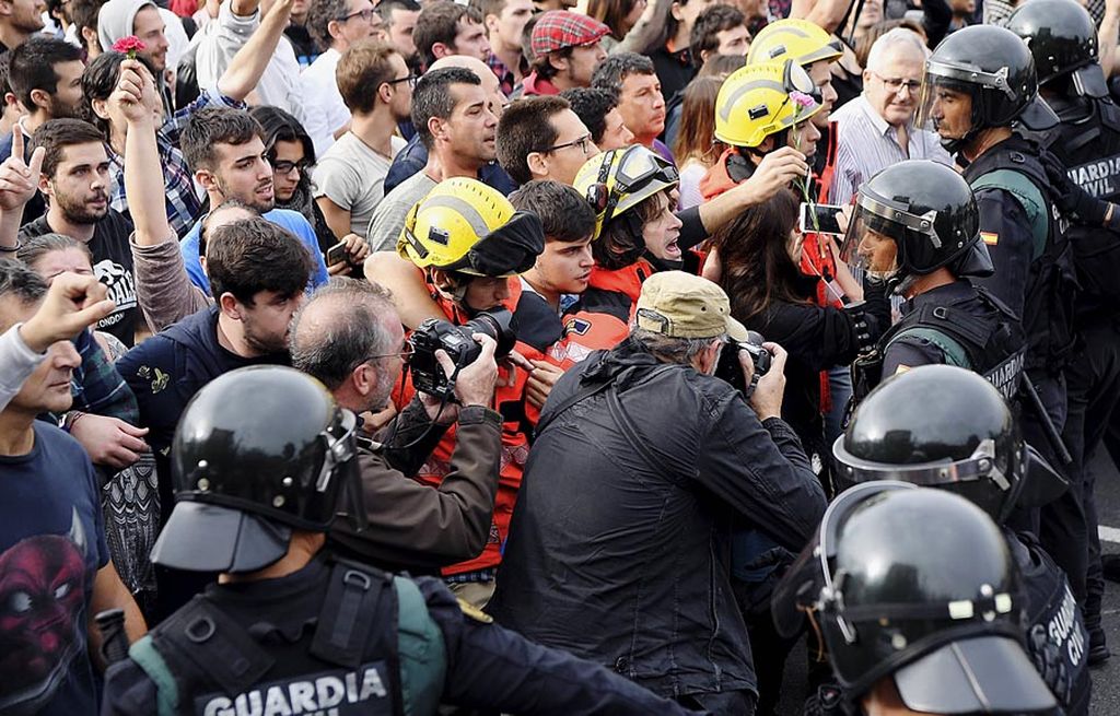 Para anggota pemadam kebakaran menahan dorongan warga di hadapan aparat keamanan sipil Spanyol di luar tempat pemungutan suara untuk referendum kemerdekaan Catalonia di San Julia de Ramis, Provinsi Girona, Spanyol, 1 Oktober lalu.