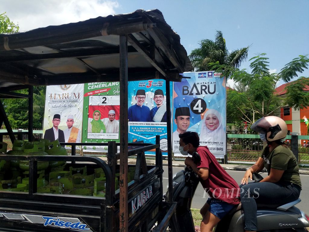 Warga, Senin (12/10/2020) berhenti di dekat spanduk empat pasangan calon yang akan bersaing di Pilkada kota Mataram, Nusa Tenggara Barat, 9 Desember 2020 mendatang.