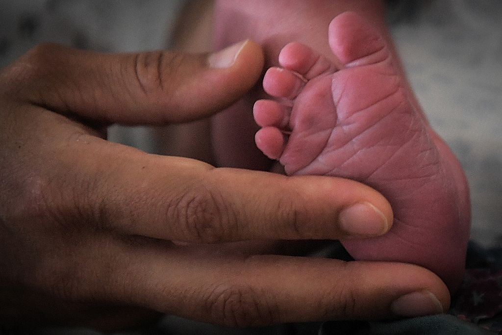 Seorang ibu memegang telapak kaki bayinya yang baru lahir di rumah sakit di Nantes, Perancis, Juli 2018. 