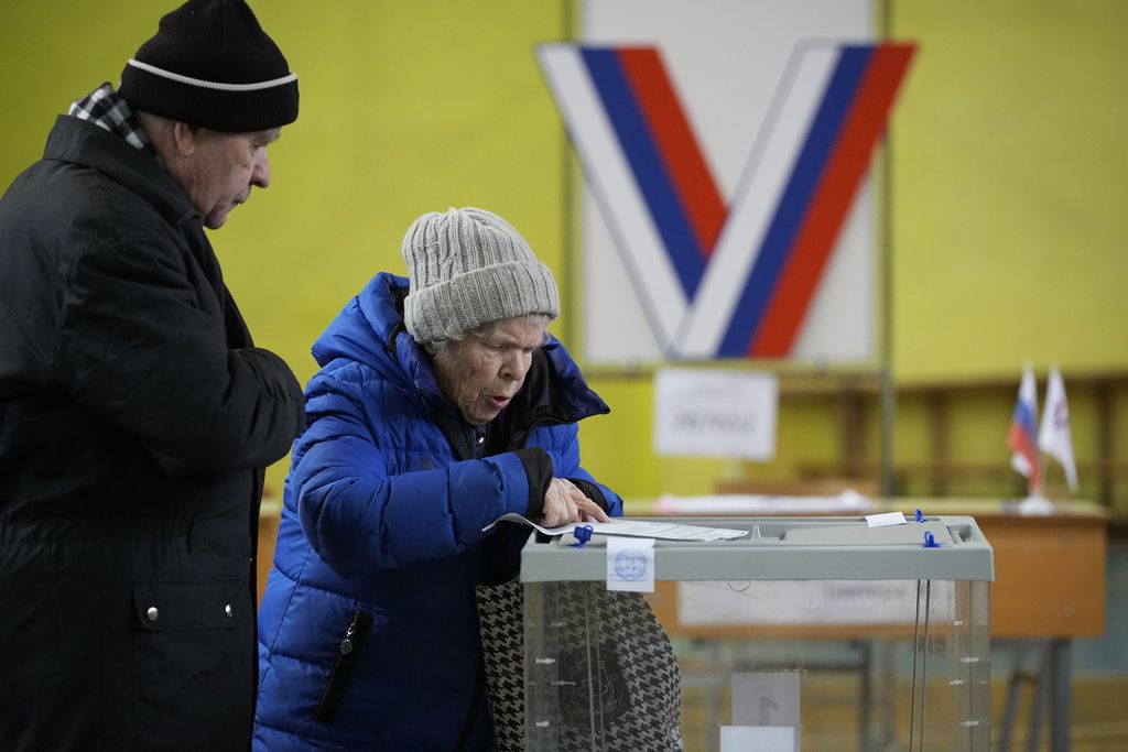 Pasangan lansia memeriksa surat suara di tempat pemungutan suara yang terletak di gimnasium sekolah selama pemilihan presiden di St Petersburg, Rusia, pada 15 Maret 2024. 