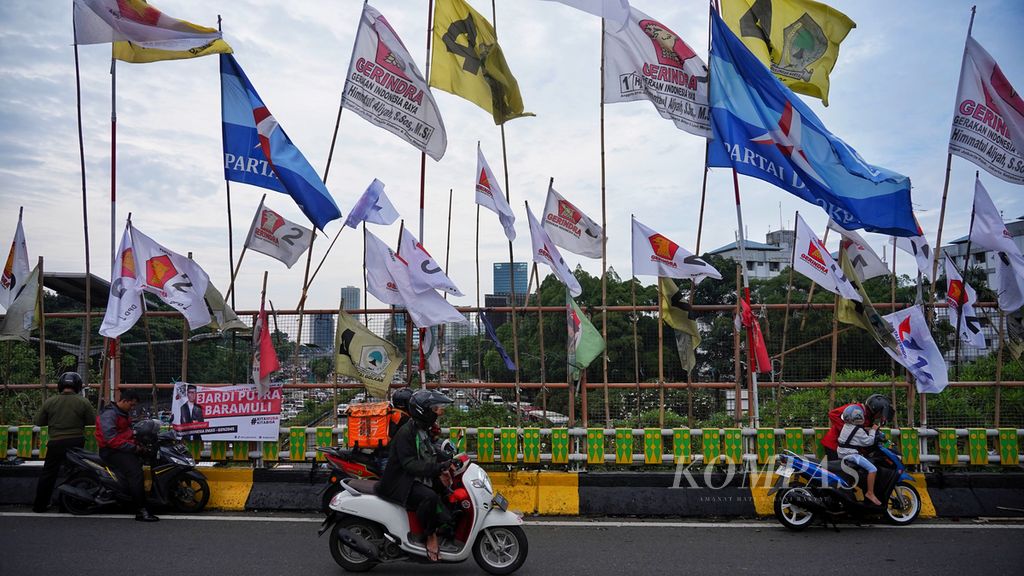 Deretan bendera partai politik terlihat masih terpasang di tepian tembok Jembatan Layang Senayan, Jakarta, Rabu (31/1/2024). Selain baliho dan spanduk, bendera parpol yang terpasang secara serampangan di tepi jalan juga membahayakan pengendara di jalan tersebut. 