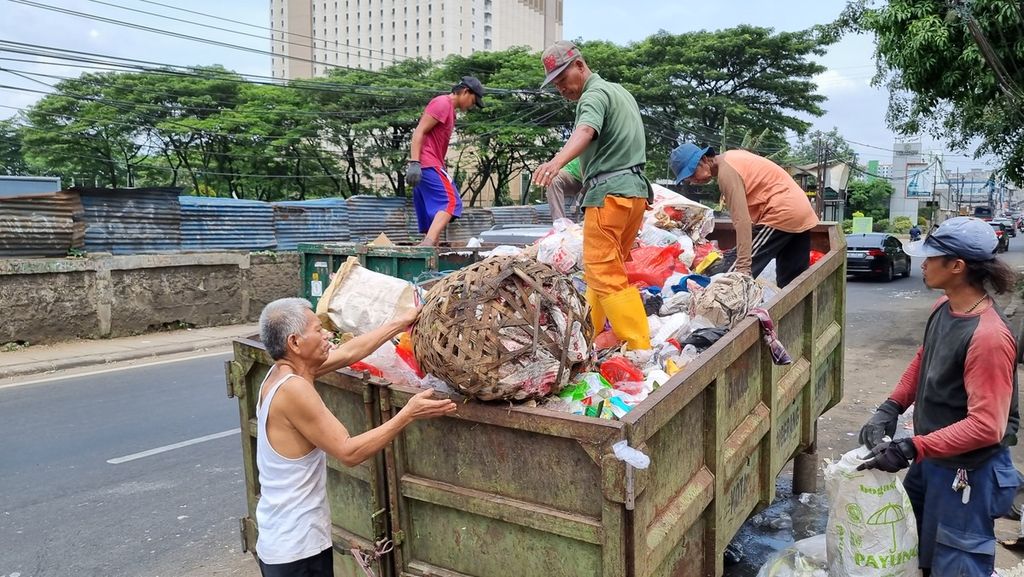 Fauzan (58), pekerja di Pasar Cimanggis, membuang sampah di tempat sampah yang disediakan petugas kebersihan Dinas Lingkungan Hidup Kota Tangerang Selatan, Rabu (18/1/2023).