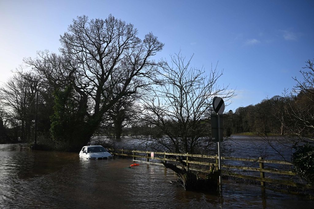 Sebuah mobil yang ditinggalkan pemiliknya terendam banjir menyusul meluapnya air Sungai Eden saat Badai Isha melanda, dekat Jembatan Warwick Bridge, Inggris barat laut, Senin (22/1/2024). 