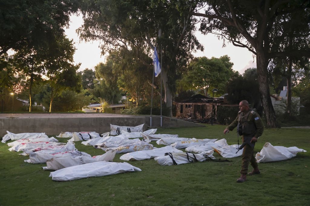 Petugas Keamanan Israel berjalan di deretan jenazah yang ditemukan di pemukiman komunal (kibbutz) Beeri yang berbatasan dengan Jalur Gaza, Rabu (11/10/2023). Beeri merupakan titik masuk Kelompok Hamas saat menyerbu Israel pada Sabtu pekan lalu. 