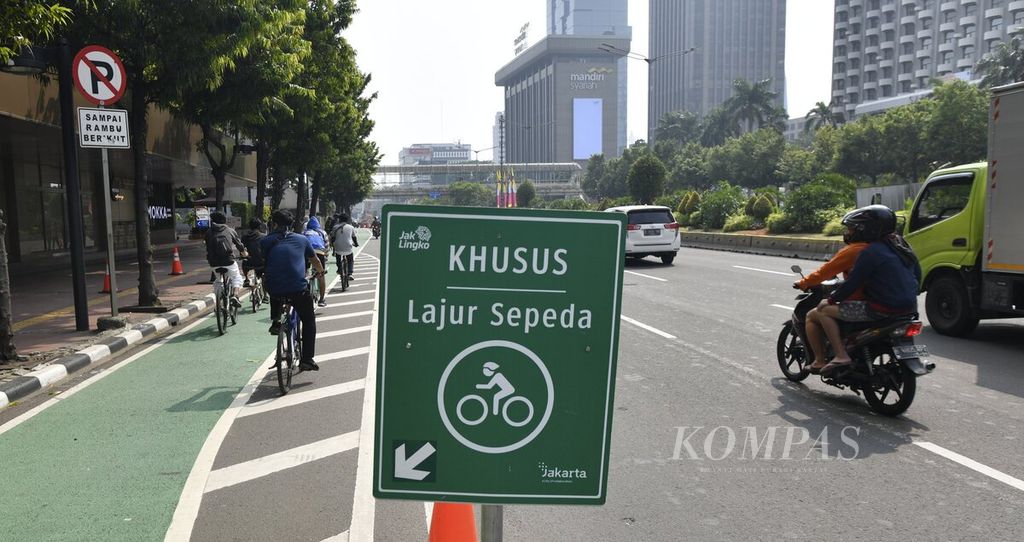 Pesepeda melintasi lajur sementara untuk sepeda (<i>pop up bike lane</i>) di Jalan MH Thamrin, Jakarta, Minggu (28/6/2020).