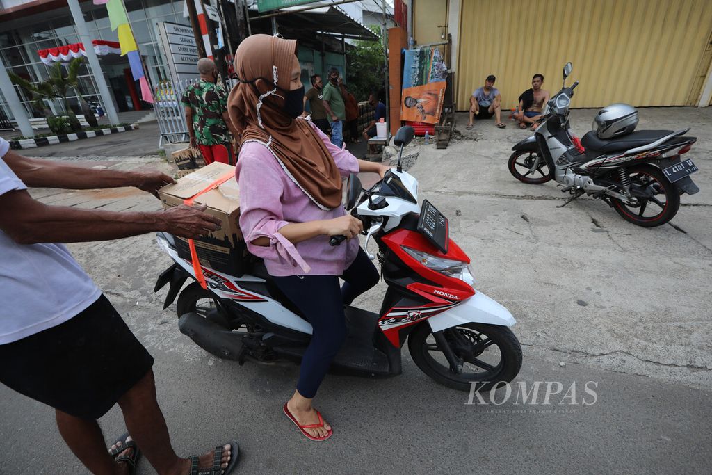 Warga mengambil bantuan sosial Pemprov DKI Jakarta dengan mengendarai sepeda motor di Kelurahan Palmeriam, Kecamatan Matraman, Jakarta Timur, akhir Juli 2020. 